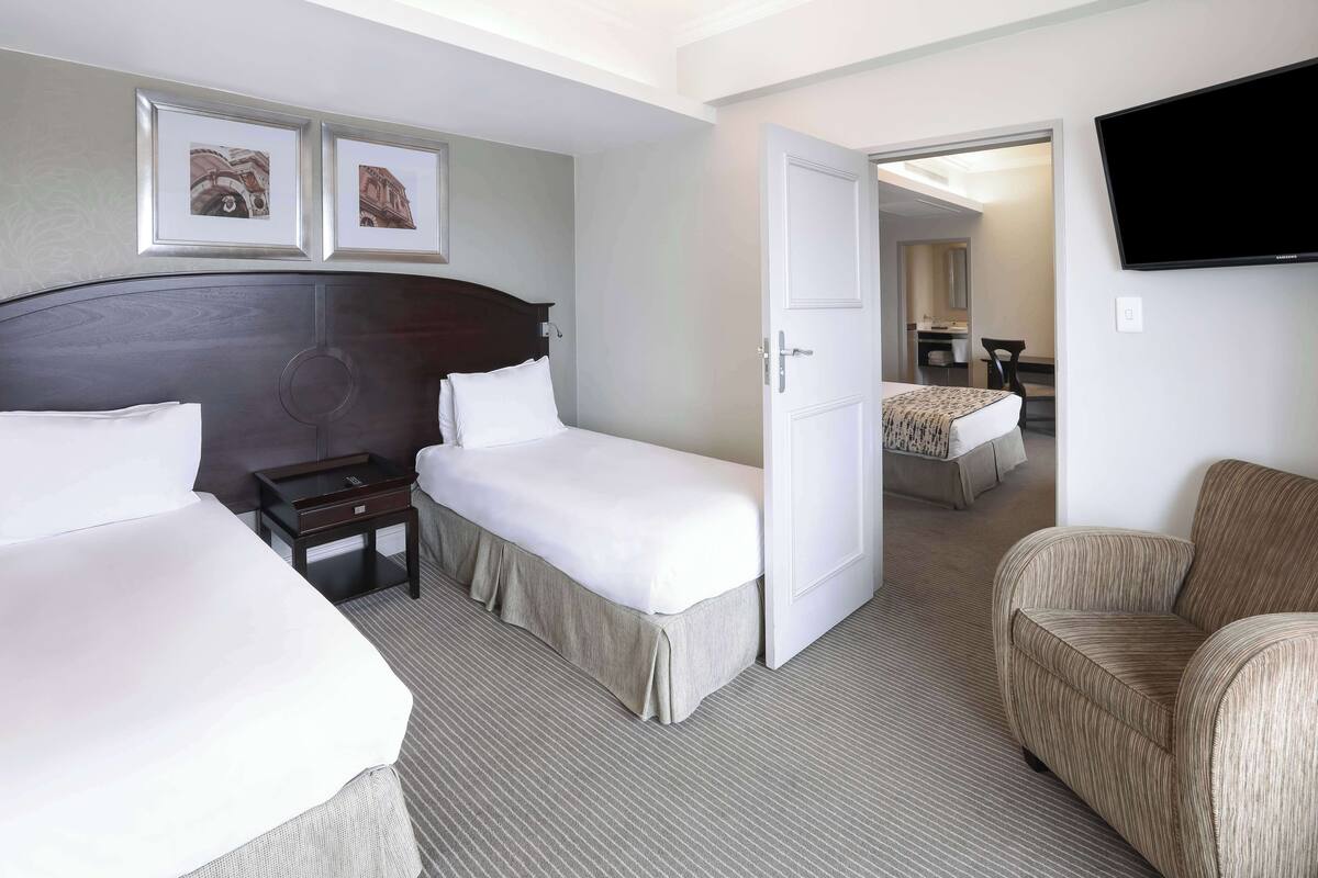 A hotel room with two beds, a TV, and a door leading to a bathroom.