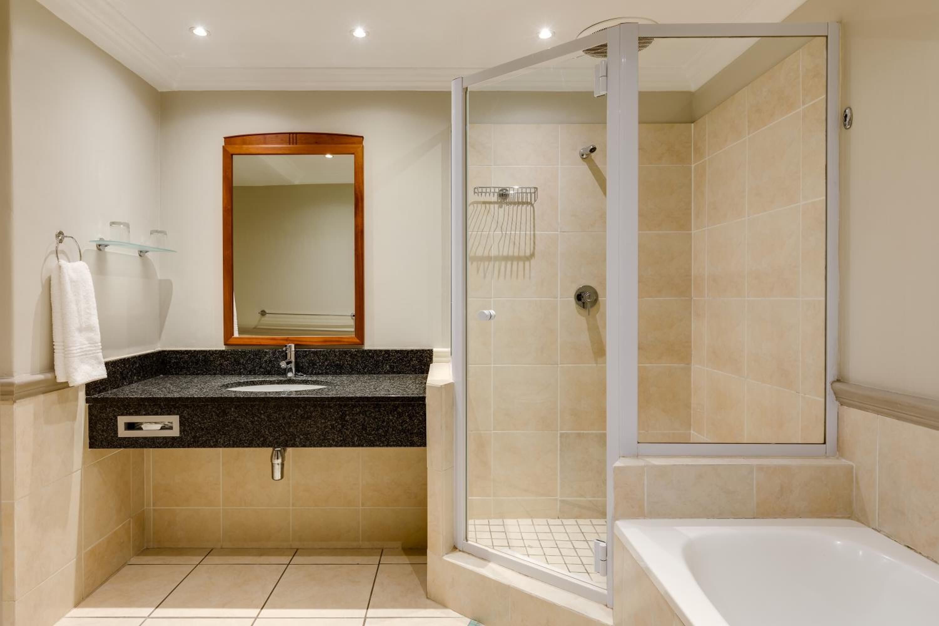 Une salle de bain moderne avec une douche à parois de verre, une baignoire sur pieds et un lavabo encastré dans un plan de travail en granit.