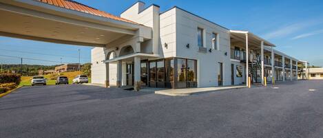 A modern building with a flat roof, large windows, and a covered entrance area.