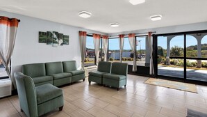 Una habitación amplia con un sofá verde, ventanas grandes con cortinas y vistas al exterior.