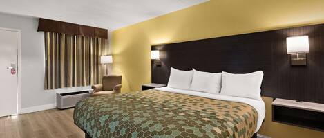 Una habitación de hotel con una cama grande, una mesita de noche, una lámpara y un estante en la pared.