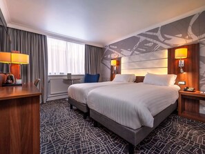 Relax in a stylish room with a large bed, desk, and two lamps.