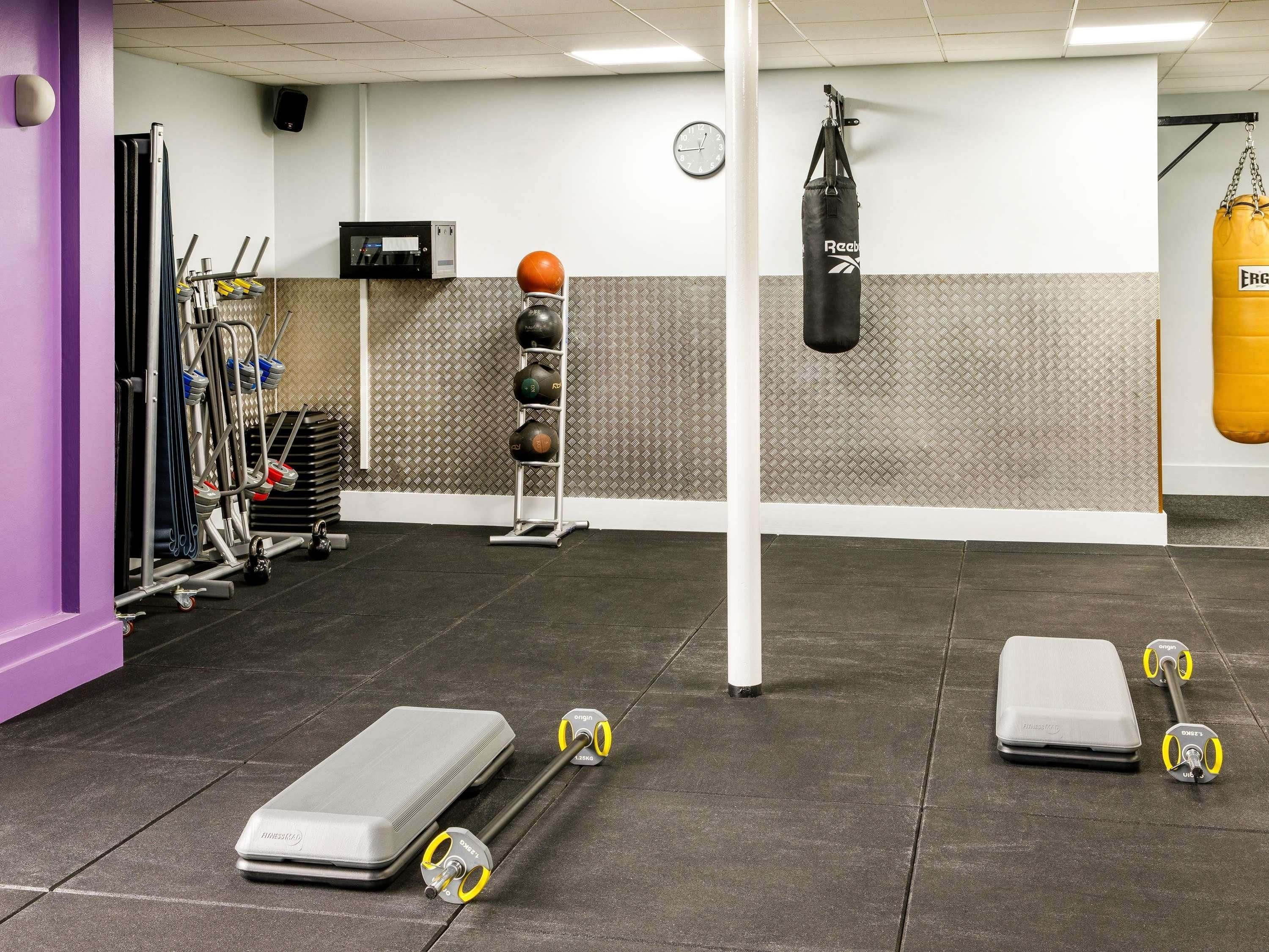 A gym with exercise equipment, a punching bag, and a wall clock.