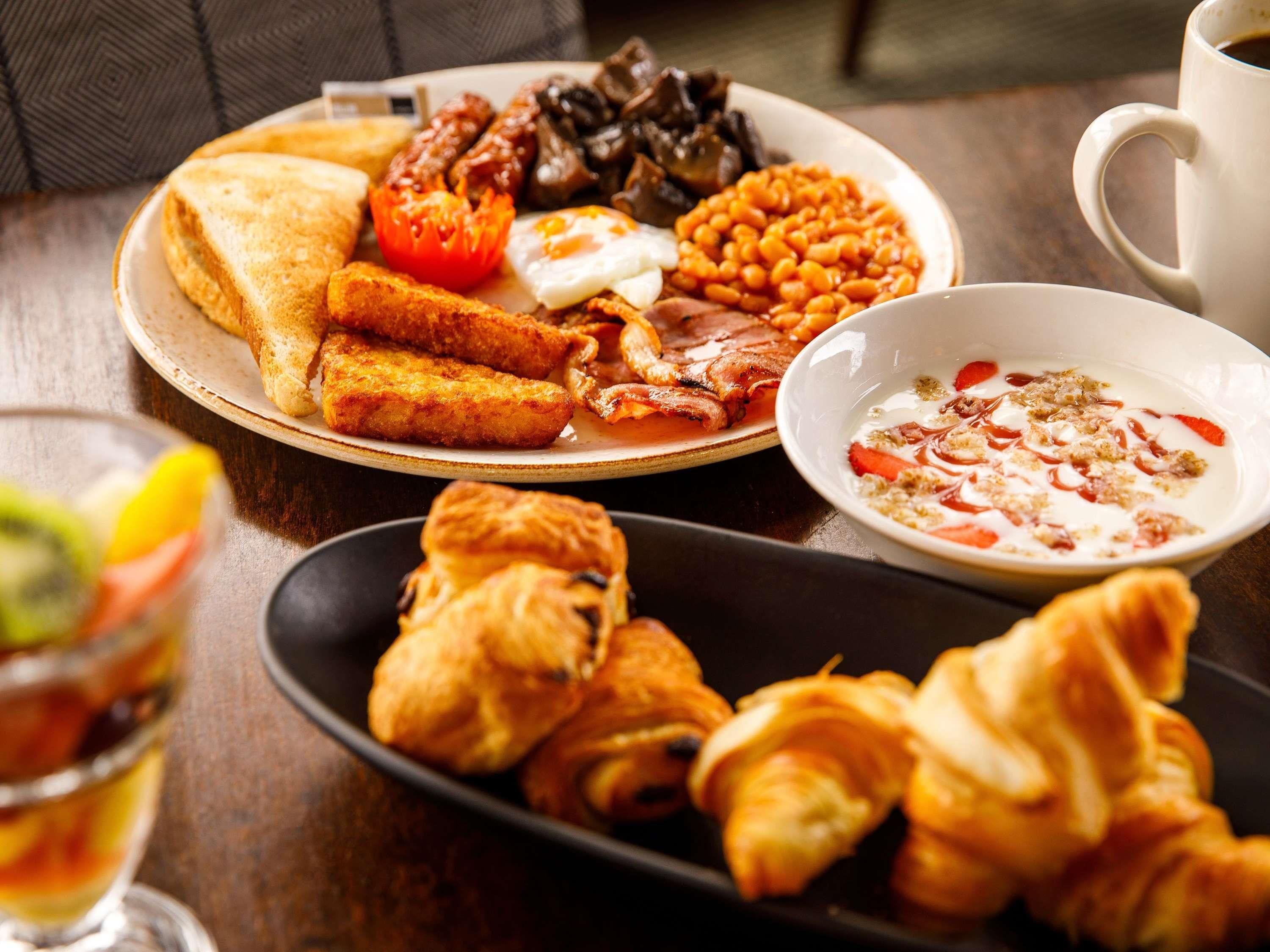 A breakfast plate with toast, eggs, beans, and sausages.