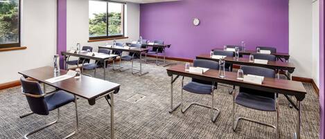 A conference room with multiple tables, chairs, and a clock on the wall.