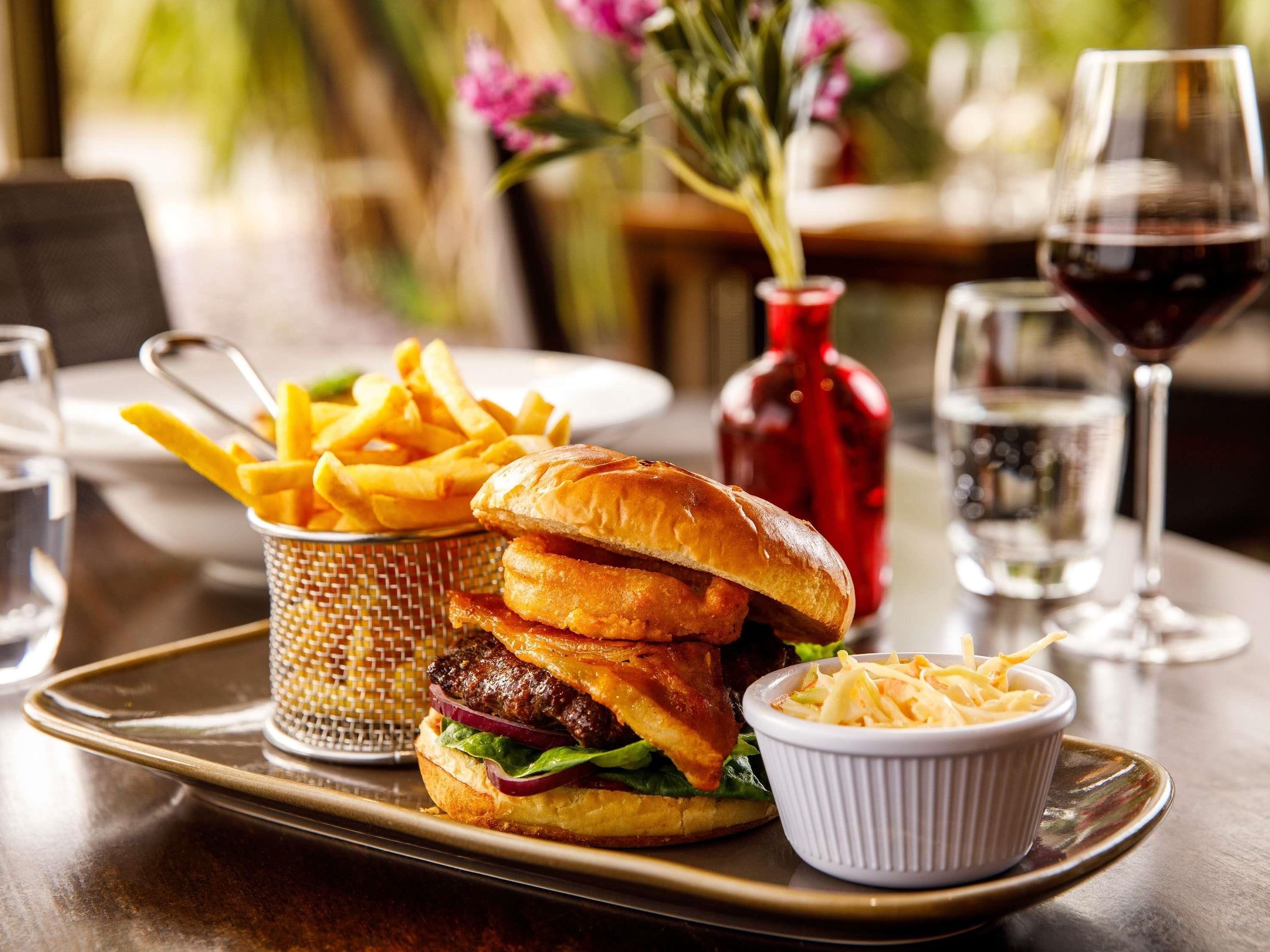 A meal consisting of a burger, fries, and a small bowl of coleslaw on a tray.