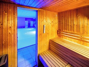 Relax in a serene sauna room with a bench and a door leading to another area.