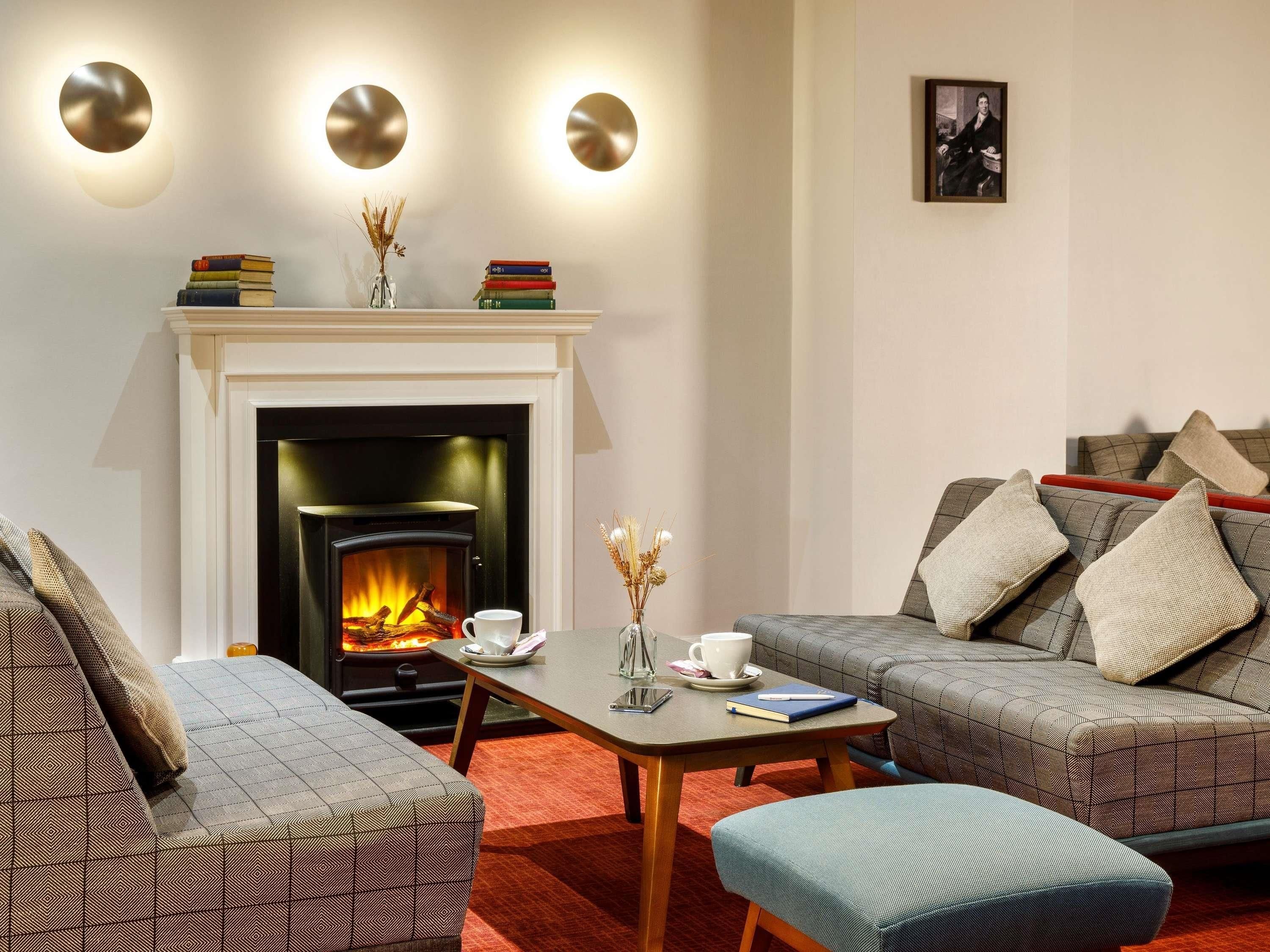Una sala de estar con chimenea, un conjunto de sofás, una mesa de centro y una estantería.