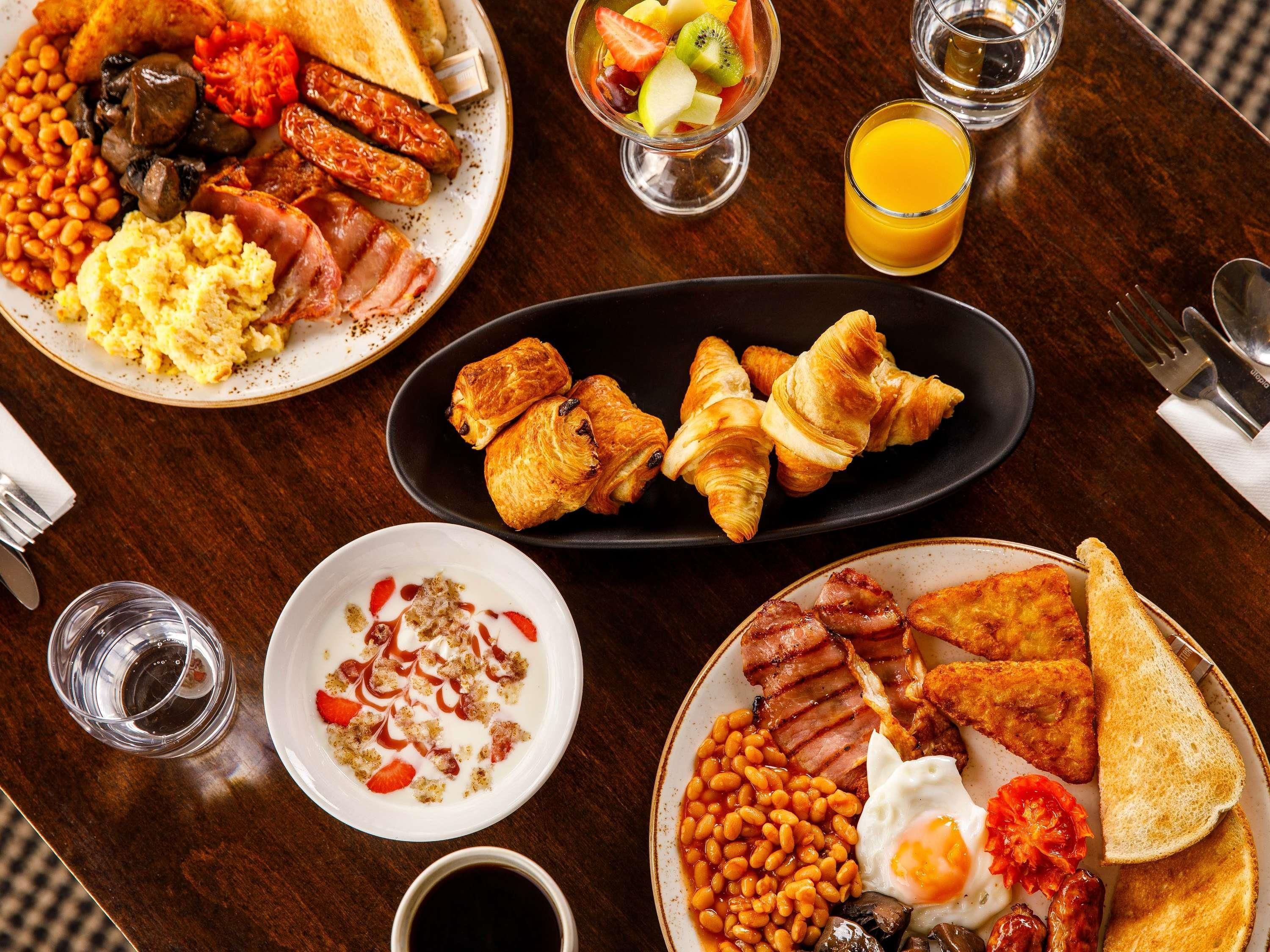 A breakfast spread with various dishes and drinks on a wooden table.