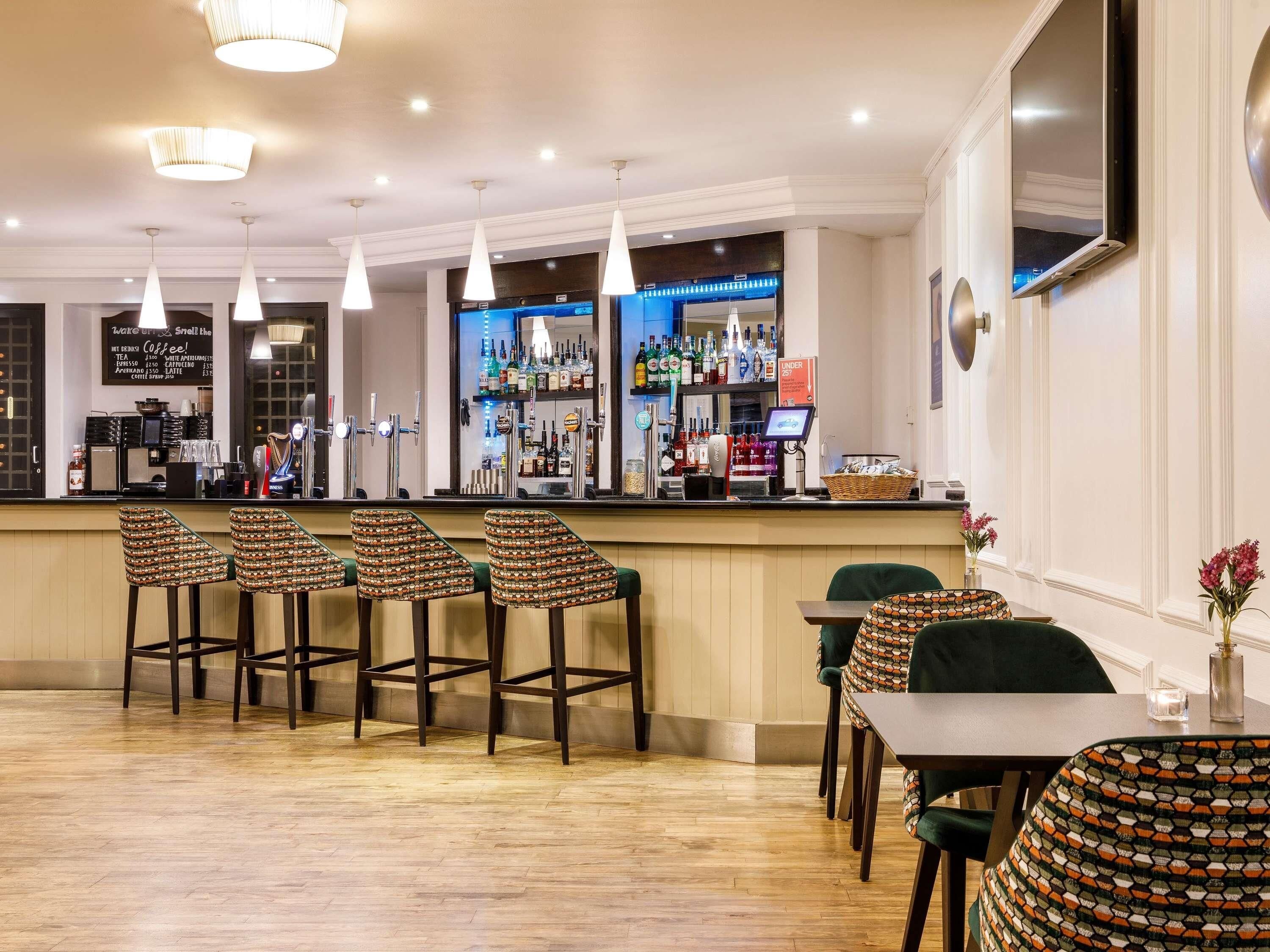 A bar area with stools, a counter, and a selection of bottles.