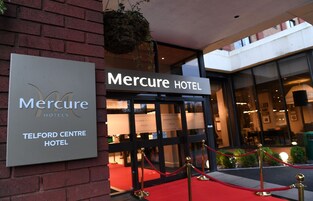El exterior del Hotel Mercure, con una entrada destacada que incluye una alfombra roja y un cartel.