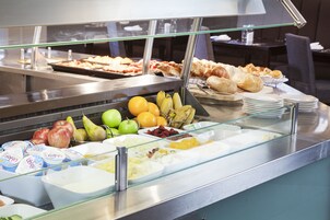 Un bufé con diversos alimentos, incluyendo frutas, pasteles y productos lácteos.