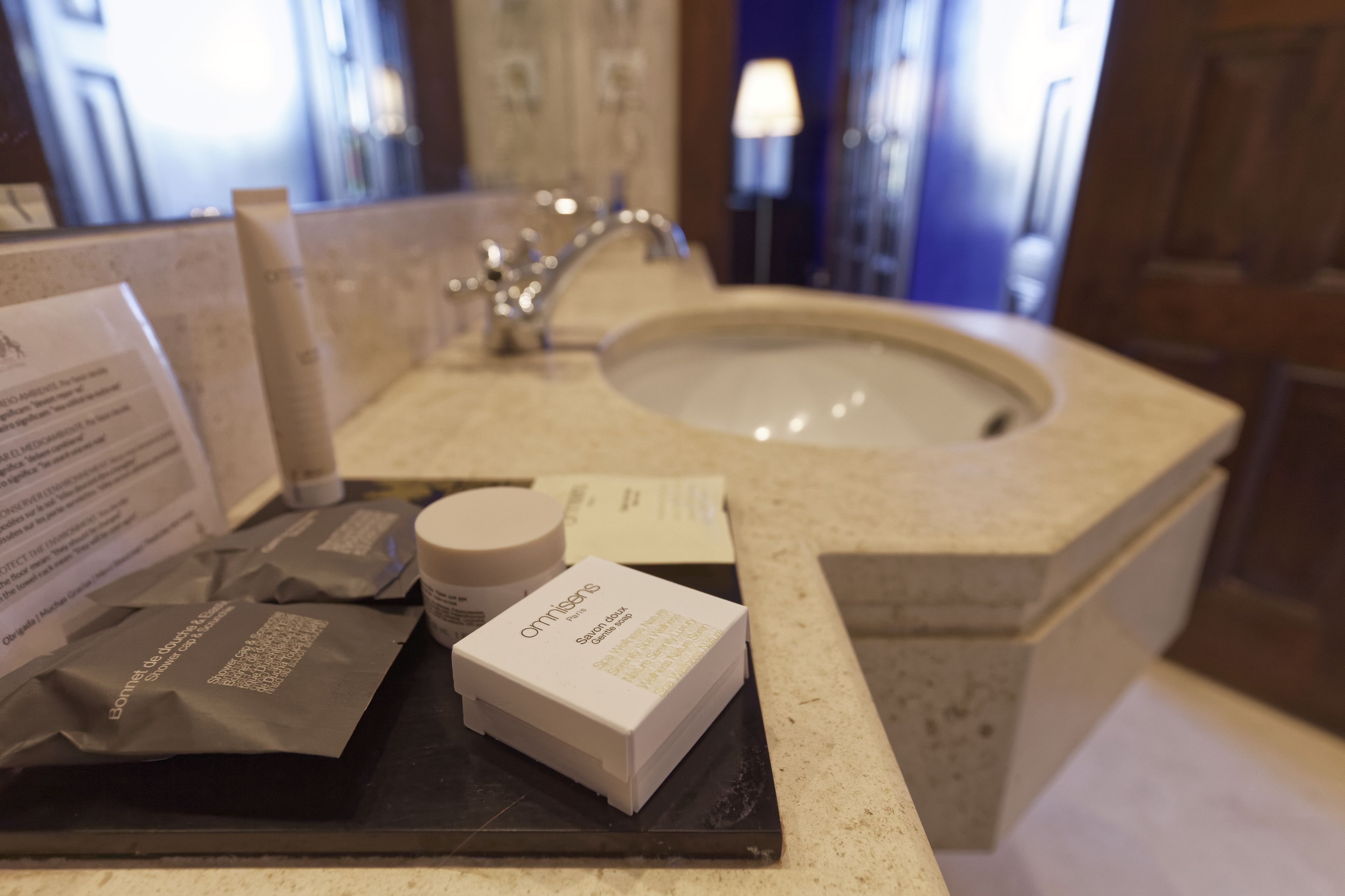 A hotel bathroom with a sink, toiletries, and a mirror.