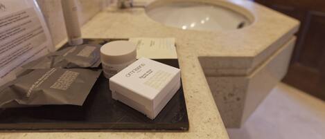 Un baño de hotel con lavamanos, artículos de aseo y un espejo.