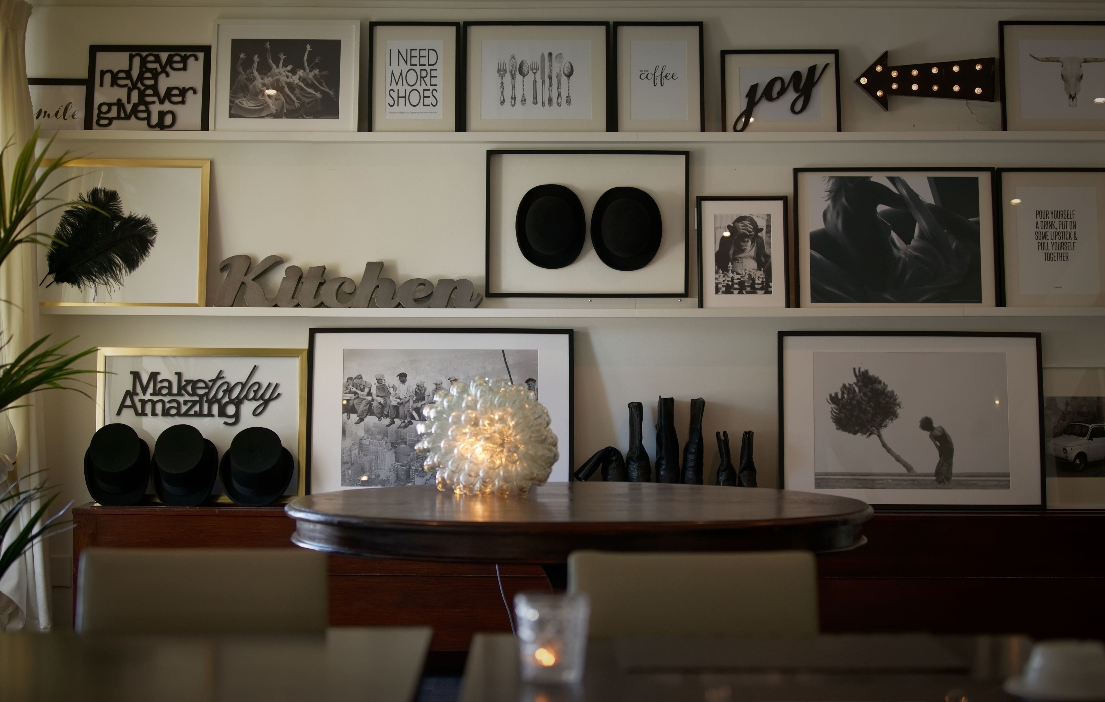 A wall with various framed pictures and text, including 'Kitchen' and 'Maketoday Amazing'.