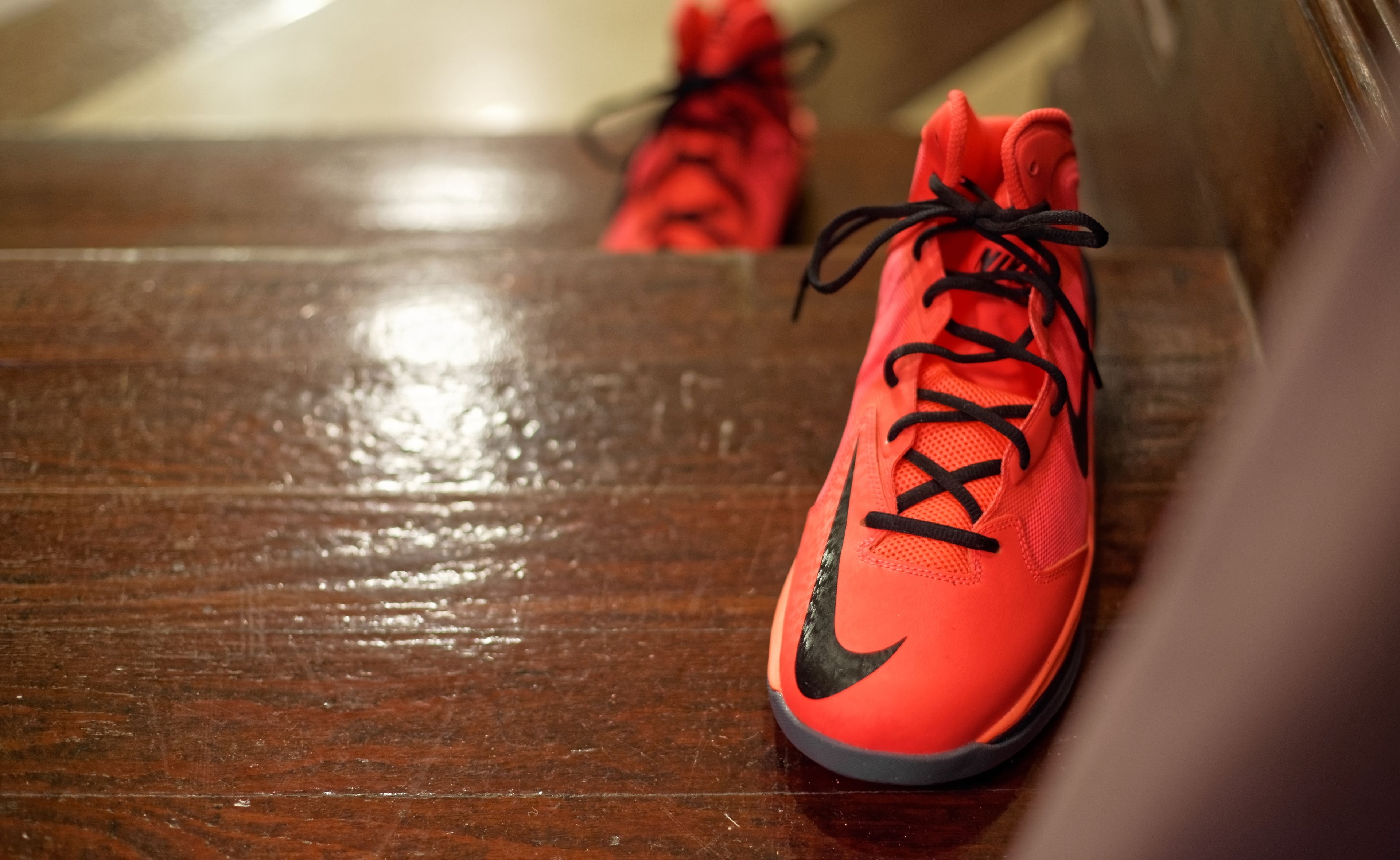 A pair of red and black sneakers on a wooden floor.
