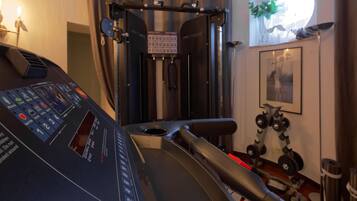 Un gimnasio con cinta de correr, máquinas de pesas y mancuernas.
