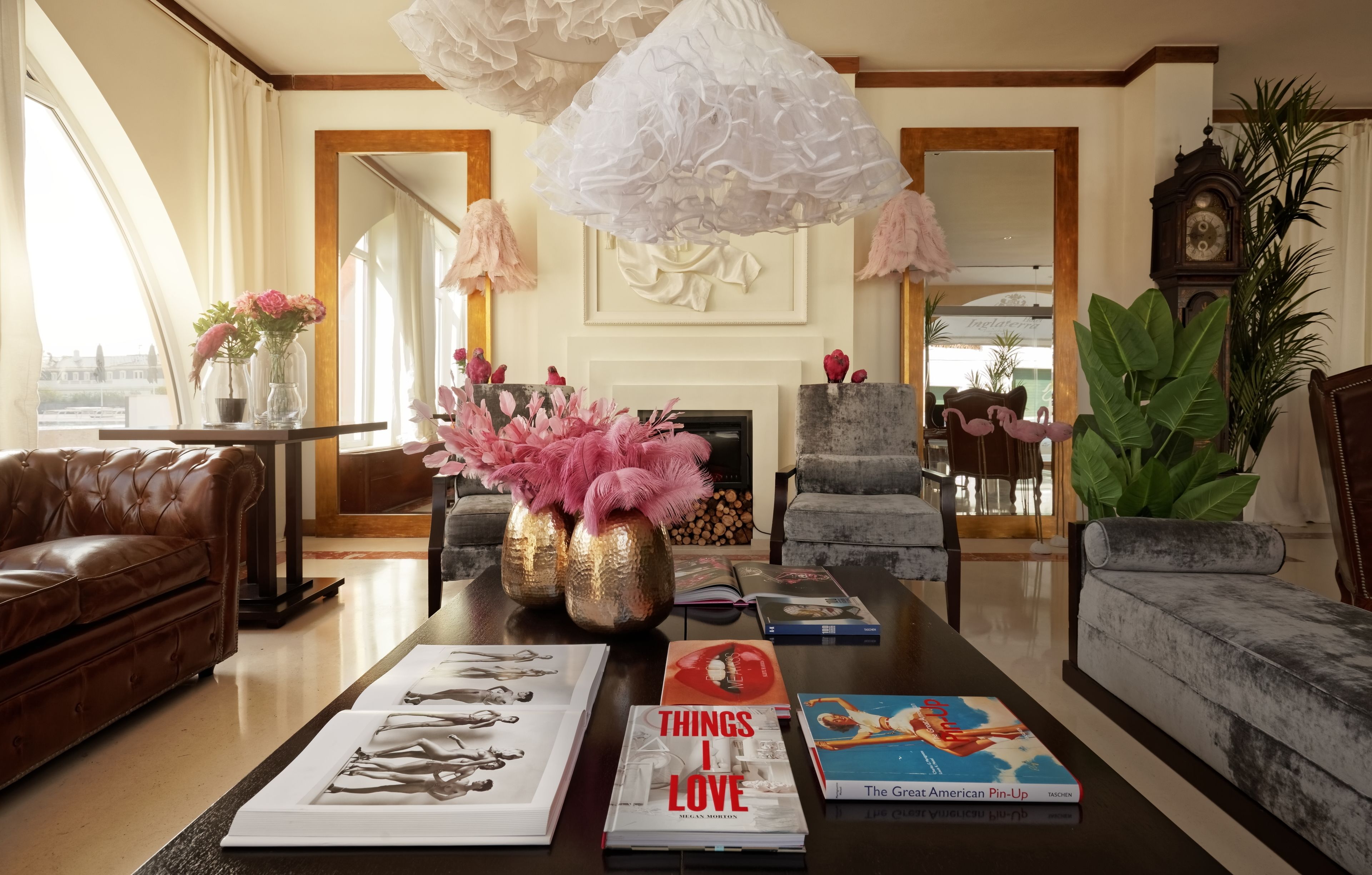 Un salón espacioso con chimenea, sofás de cuero, una mesa de centro con libros y jarrones decorativos.