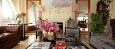 Un salón espacioso con chimenea, sofás de cuero, una mesa de centro con libros y jarrones decorativos.