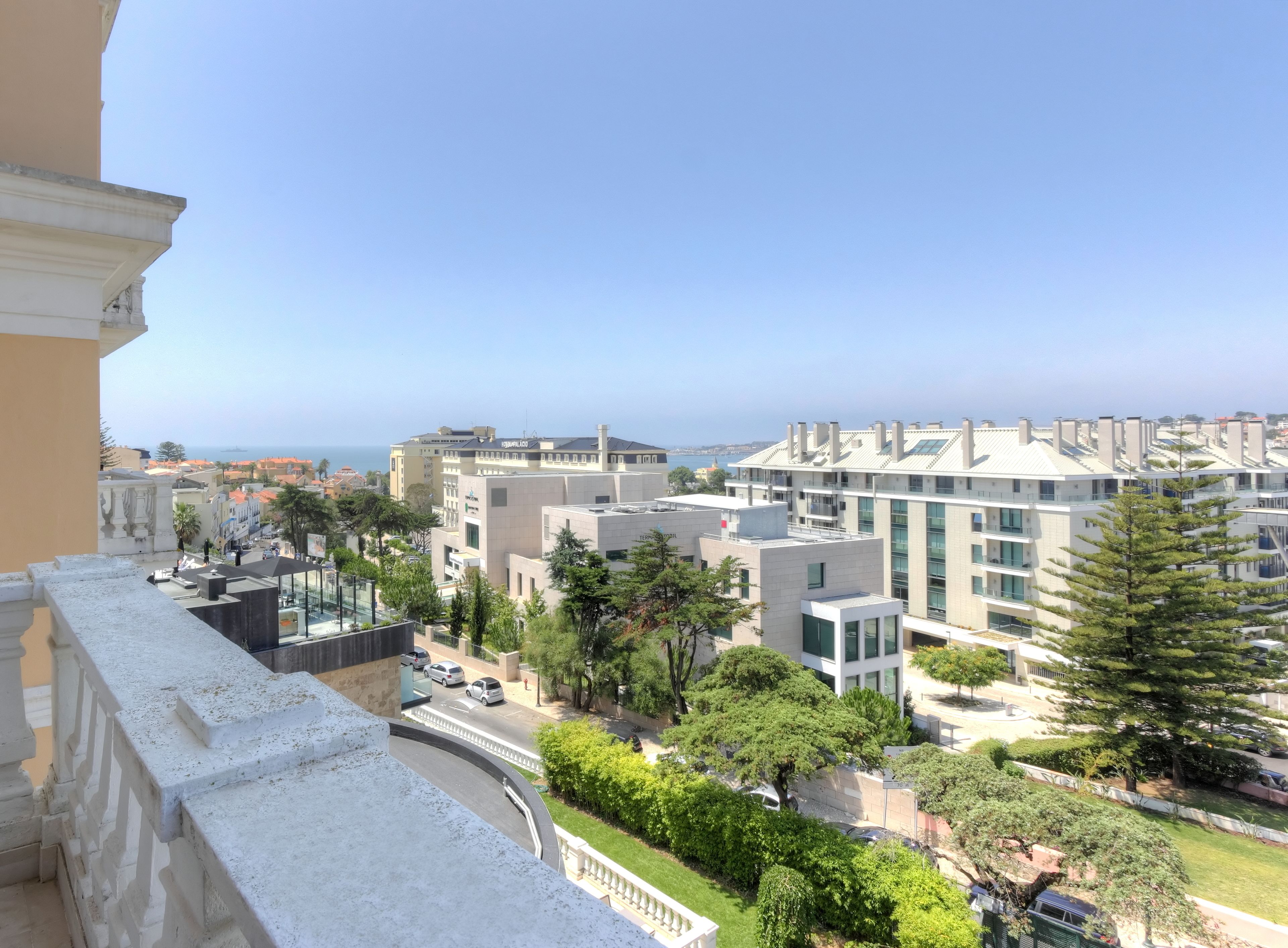Un paisaje urbano moderno con edificios contemporáneos, cielo despejado y vista al mar.