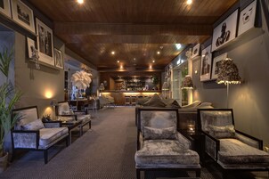 A spacious lounge area with multiple seating options, a bar in the background, and framed artwork on the walls.