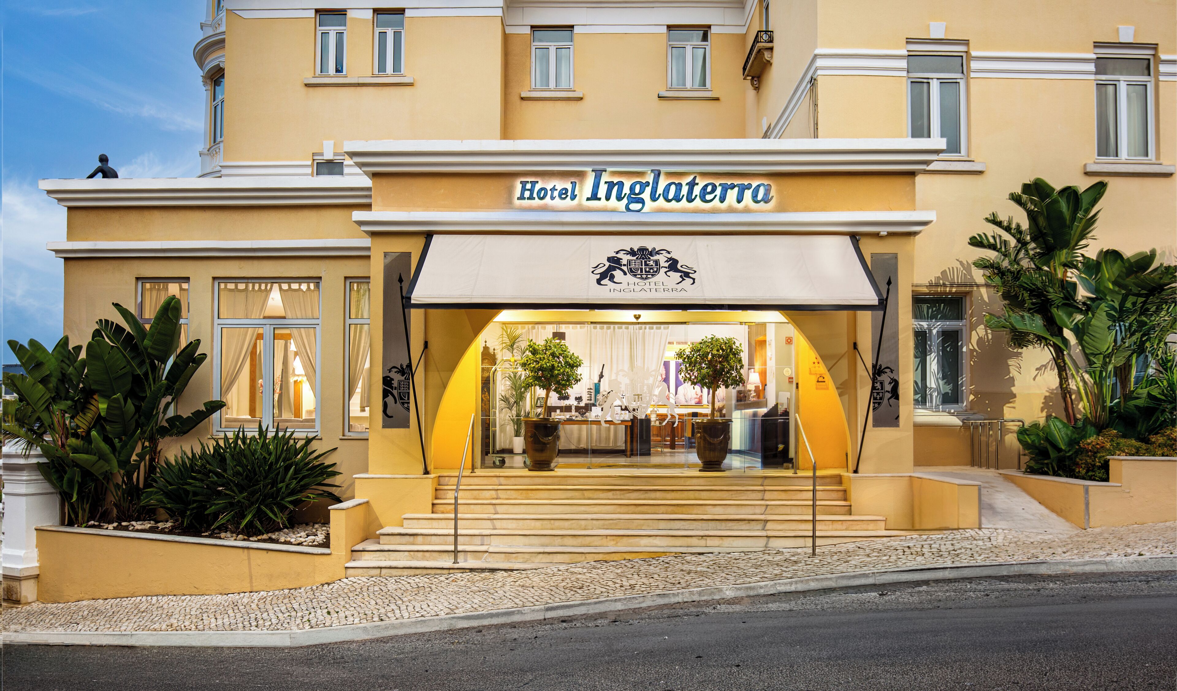 A hotel entrance with a sign reading 'Hotel Inglaterra,' featuring a traditional facade with a balcony and potted plants.