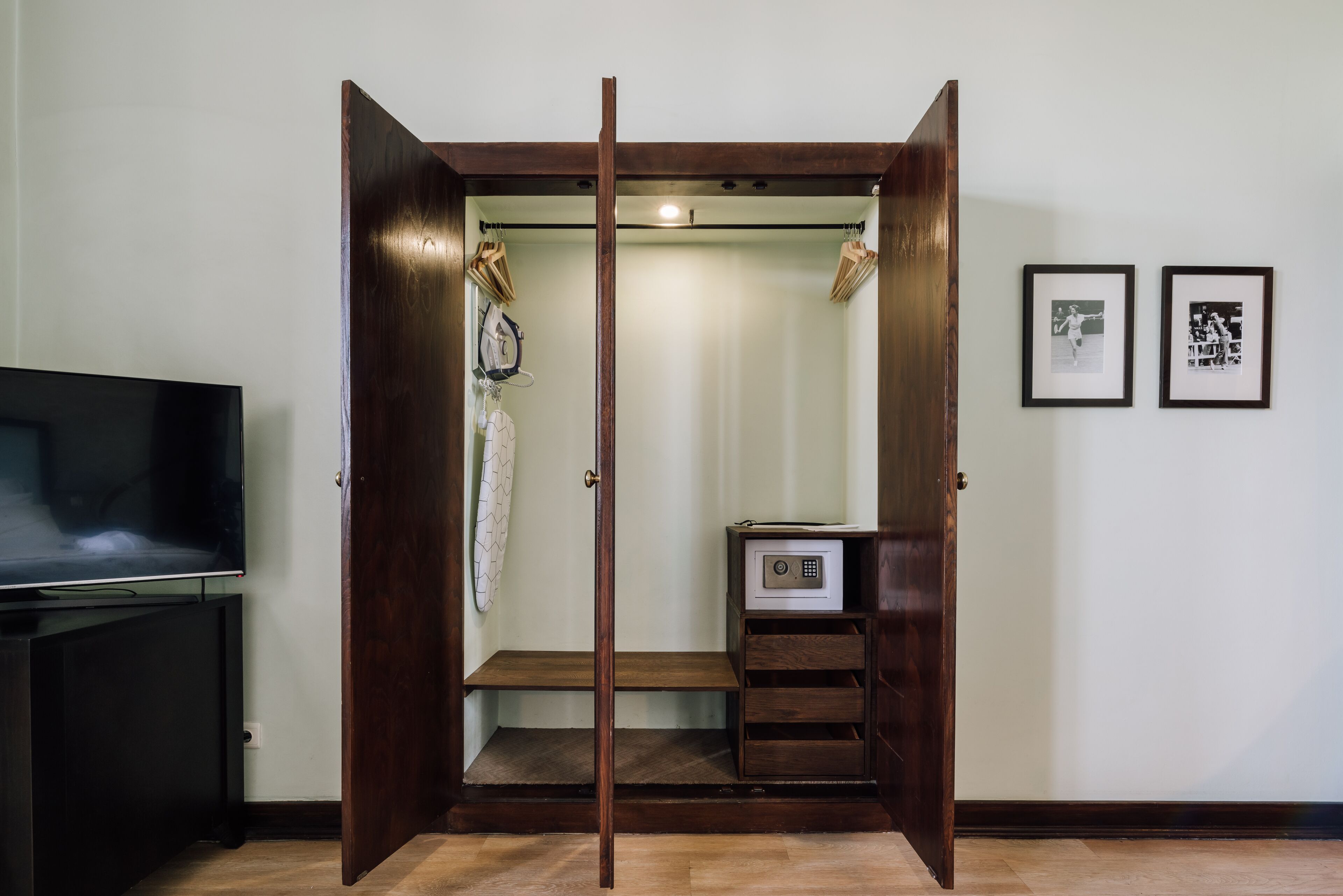 Un dressing avec des portes en bois, un petit coffre-fort et un téléviseur posé sur un meuble.