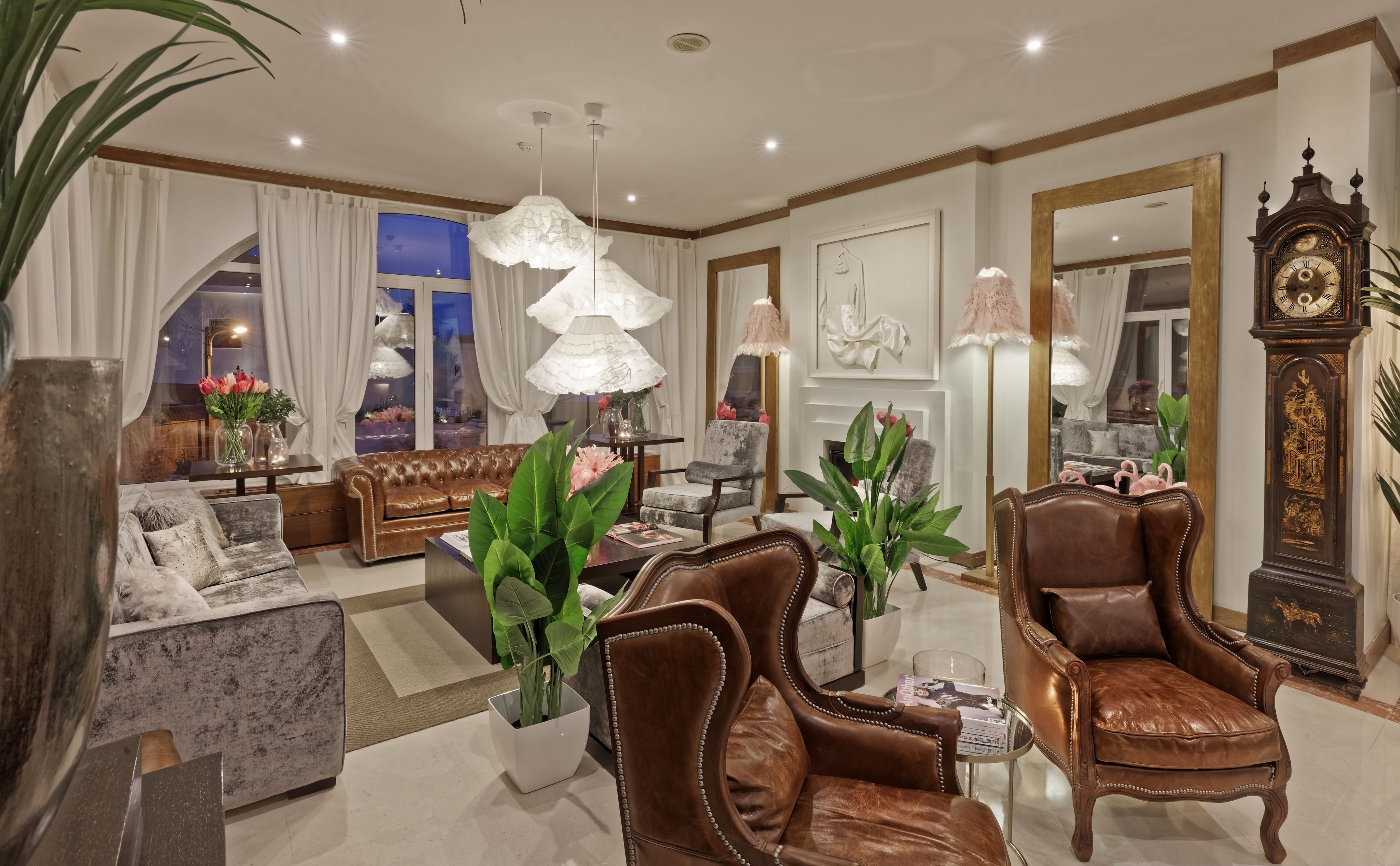 A spacious living room with a leather sofa, armchairs, and a dining area.