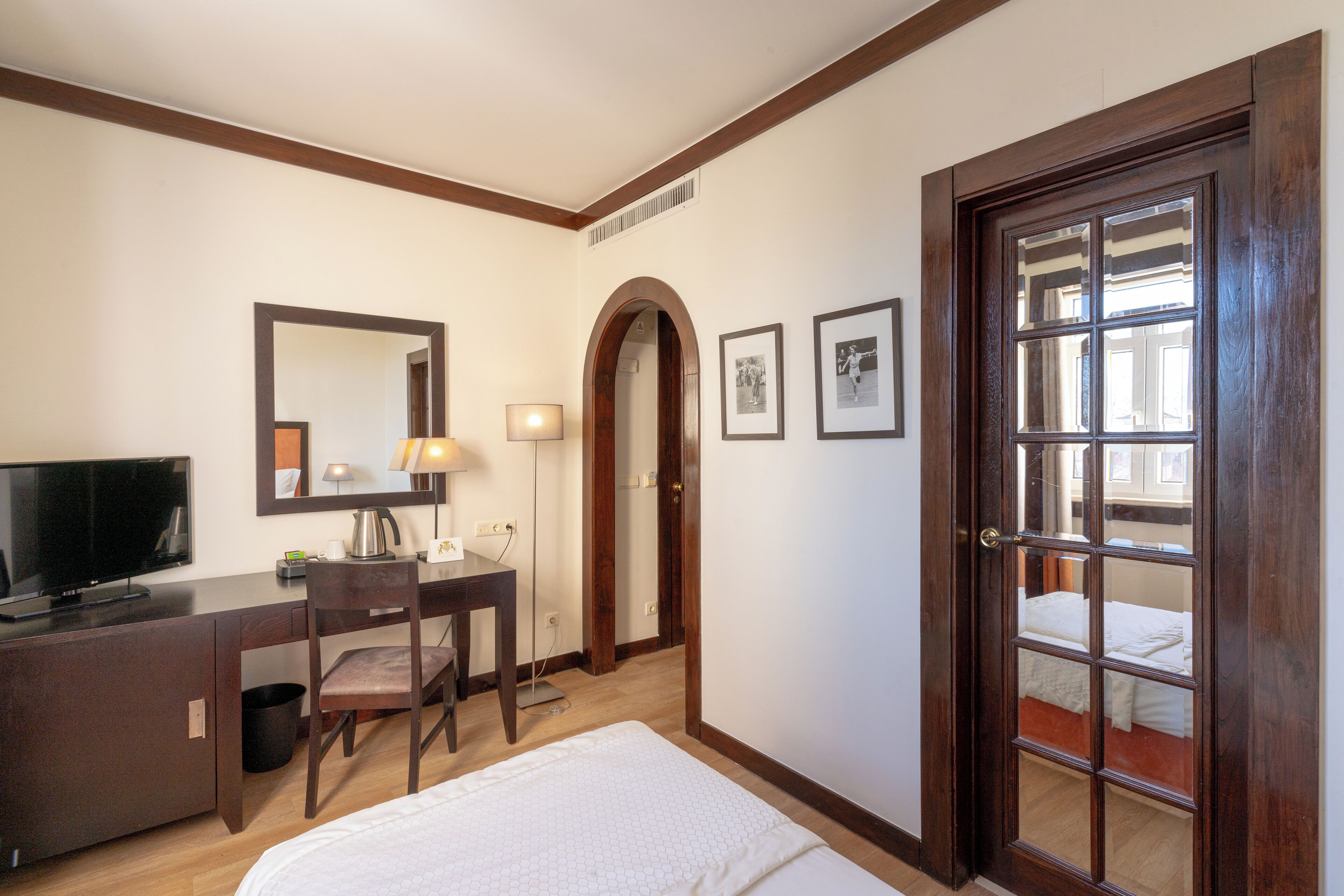Une chambre d’hôtel comprenant un lit, un bureau avec une chaise, une tél évision et une porte avec une fenêtre.