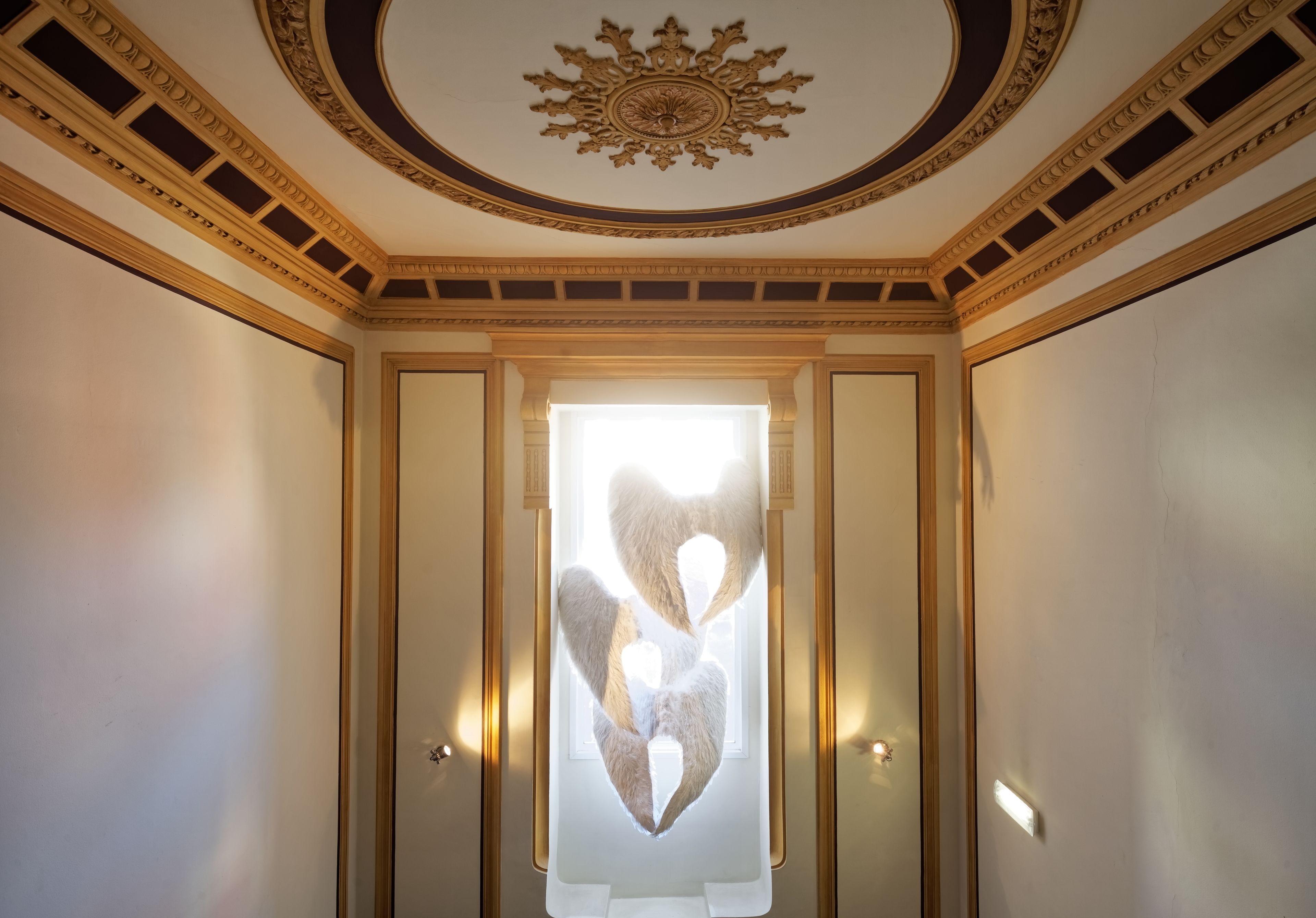 Une pièce dotée d’un plafond décoratif, d’une fenêtre en forme de cœur et d’un luminaire.