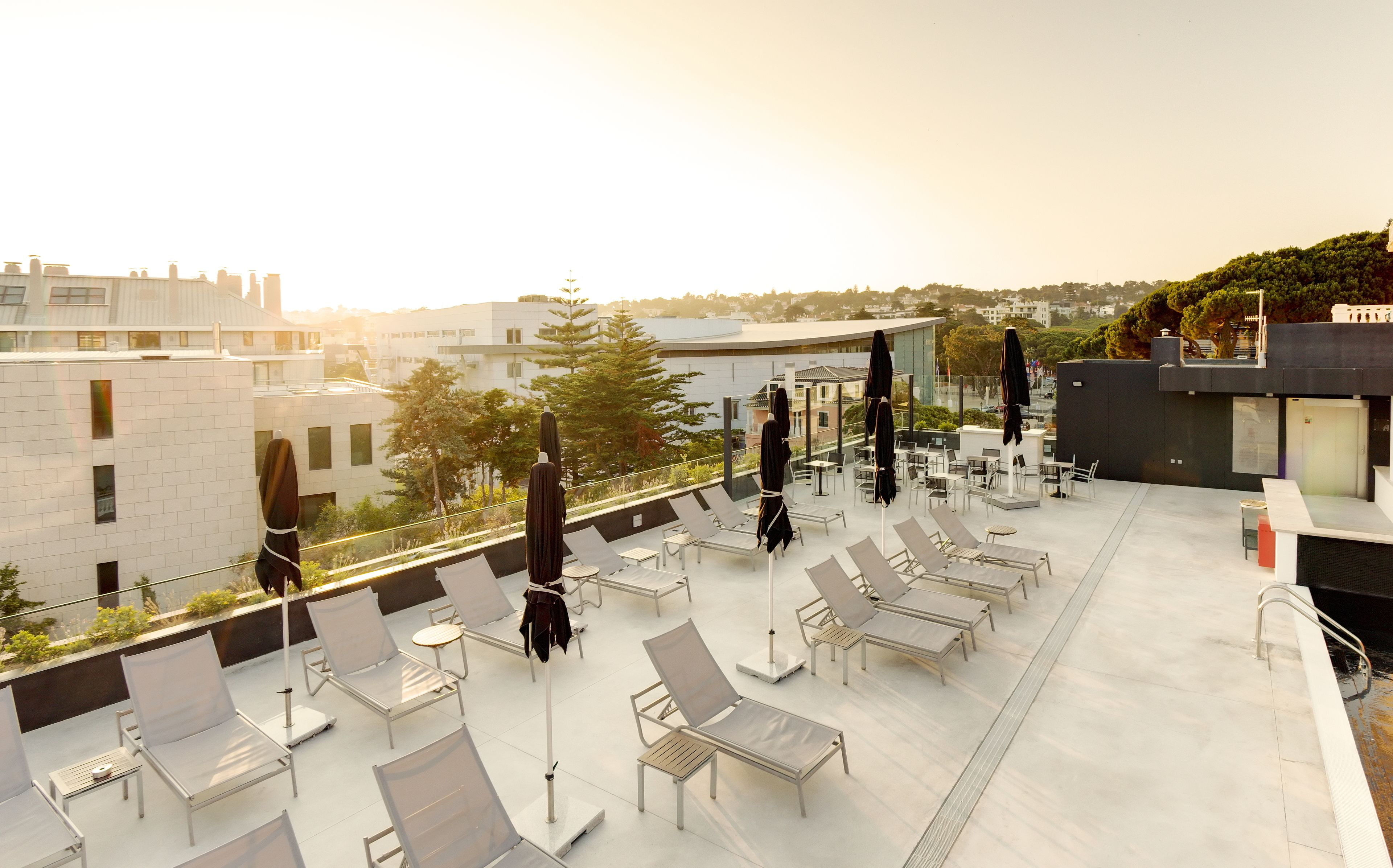 Una terraza en la azotea con tumbonas, sombrillas y vistas a la ciudad.