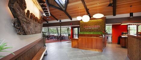 A spacious interior with a wooden reception desk, a bench, and a large wall sculpture.