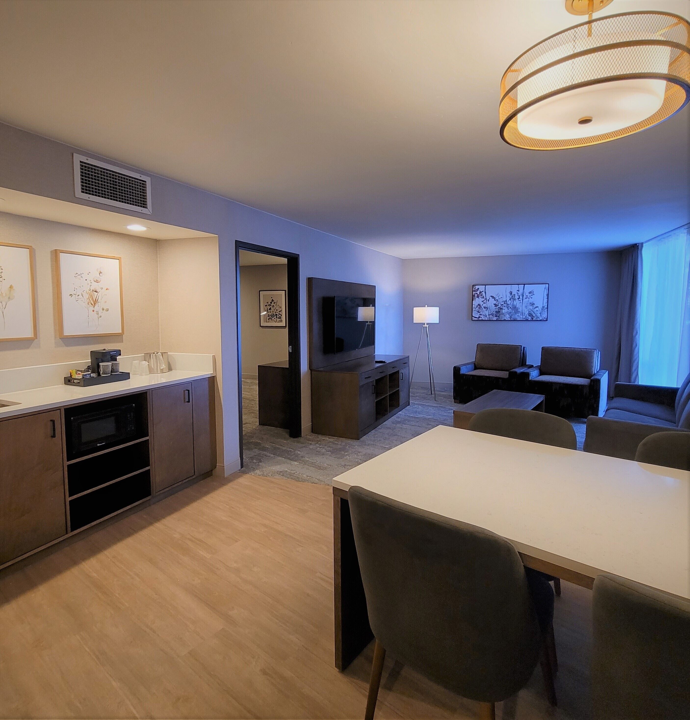 Une chambre d’hôtel moderne dotée d’un coin repas, d’une kitchenette et d’un espace salon.