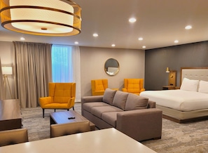 A hotel room with a bed, two armchairs, a sofa, a round mirror, a floor lamp, and a bedside table. - The Riverside Hotel, BW Premier Collection (Boise)