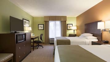 Hotelkamer met twee bedden, een bureau, een stoel, een televisie en een raam met gordijnen.