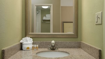 A bathroom with a granite countertop, a sink, and a mirror.