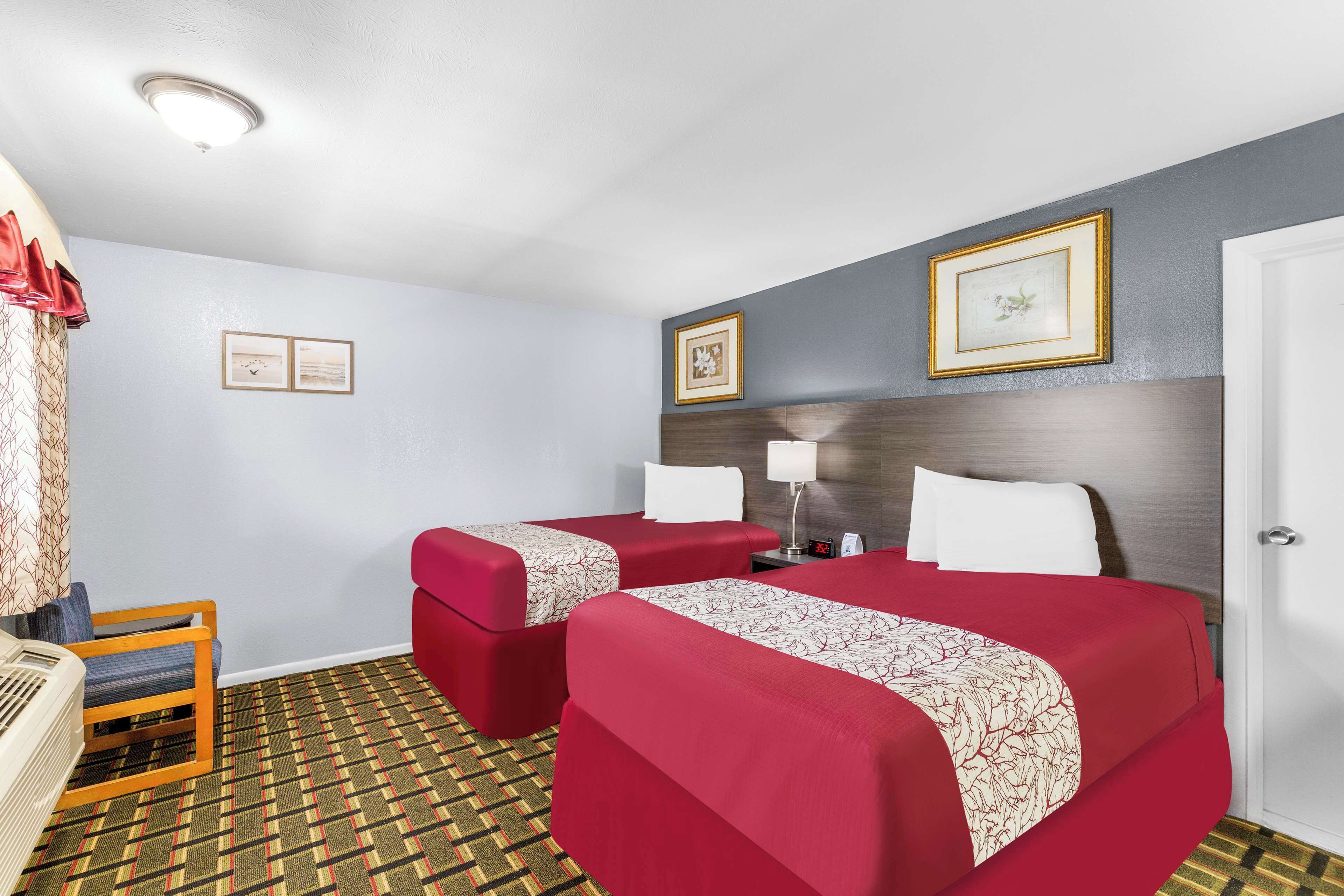 A hotel room with two beds, a desk, and a chair.