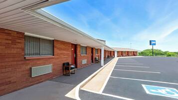 Un motel con una hilera de habitaciones, un estacionamiento techado y un espacio de estacionamiento para discapacitados.