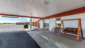 A covered outdoor area with a swing seat, a bench, and a small table. - Americas Best Value Inn Belleville (Belleville)