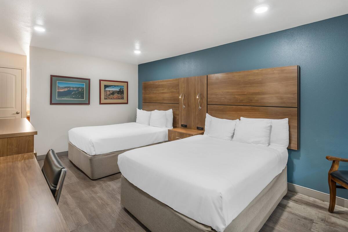 Ett hotellrum med två sängar, ett skrivbord och en stol. Det finns två inramade tavlor på väggen.