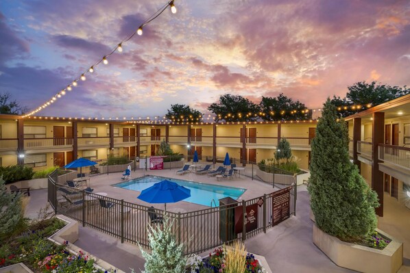 A hotel courtyard with a swimming pool, lounge chairs, and string lights. - Best Western Plus Clocktower Inn (Billings)
