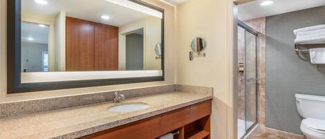 A modern bathroom with a large mirror, a sink, and a shower area.