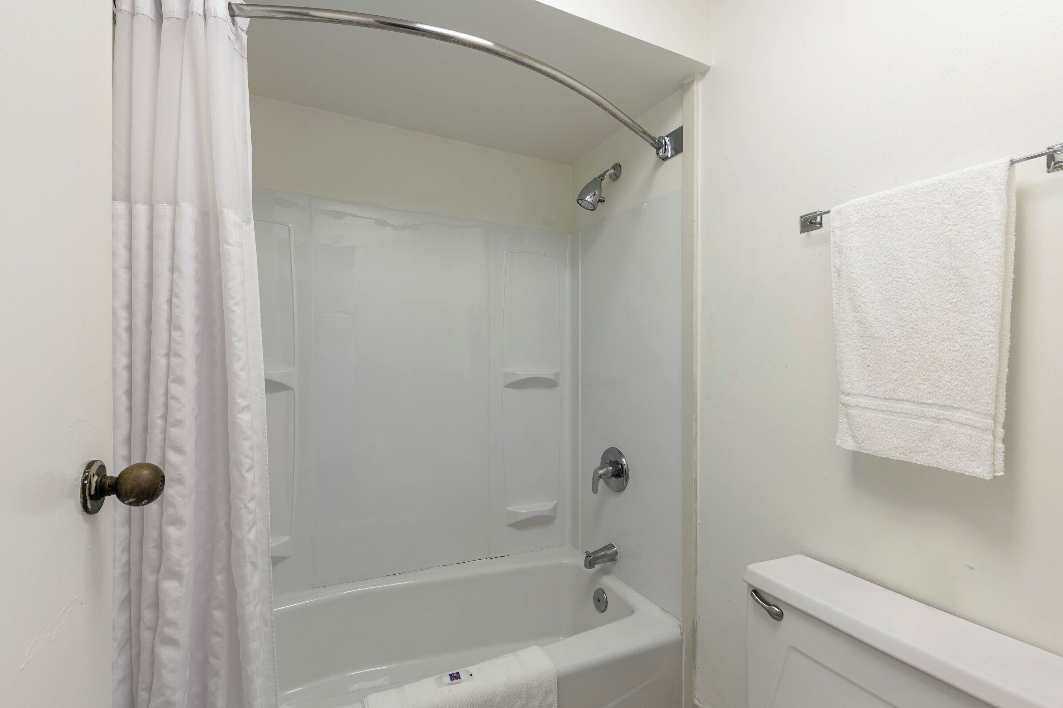 A bathroom with a shower, a toilet, and a towel hanging on the wall.