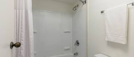 Un baño con ducha, inodoro y una toalla colgada en la pared.