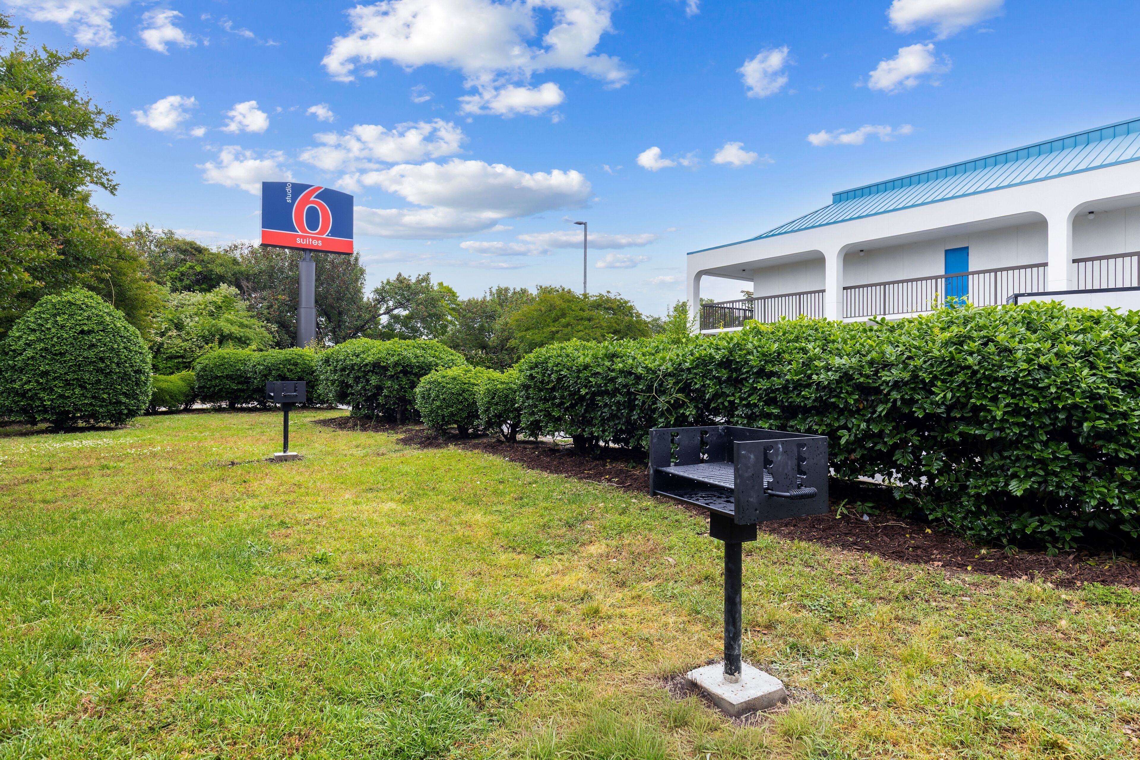 A hotel sign with the number 6, a building with a blue roof, and well-maintained hedges.