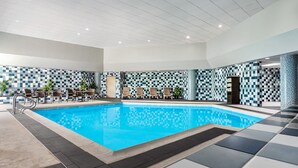 Una piscina con paredes de azulejos y sillas de descanso.
