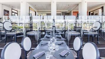 Een restaurant met gedekte tafels, met een modern design, glazen scheidingswanden en uitzicht op de omgeving.