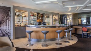Una zona de bar con una barra curva, taburetes y una variedad de botellas y vasos.