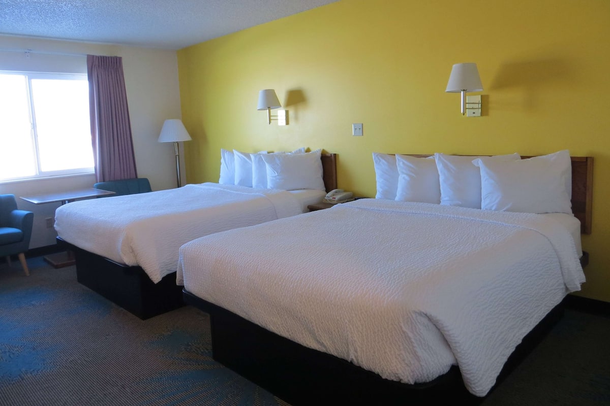 Una habitación de hotel con dos camas, un escritorio y una silla.
