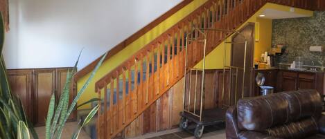 Eine Treppe mit Holzwangen, ein Ledersofa und ein Küchenbereich mit Schränken und einer Arbeitsplatte.